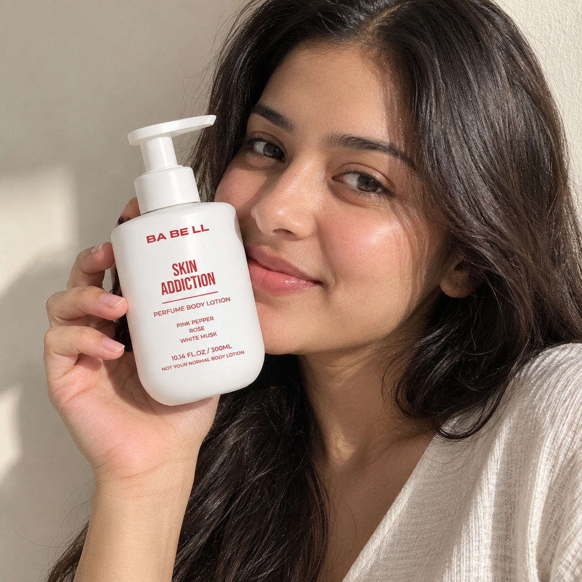 Woman holding a Babell Skin Addiction perfume body lotion 300ml bottle beside her face