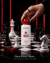 A hand with black nail polish reaches for the red cap of a white perfume bottle labeled &