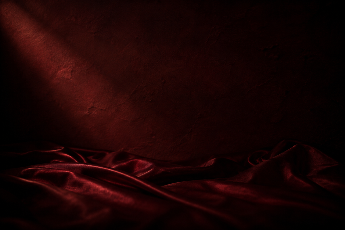 Folds of deep red silk against a burgundy plaster wall, lit by a single shaft of warm light